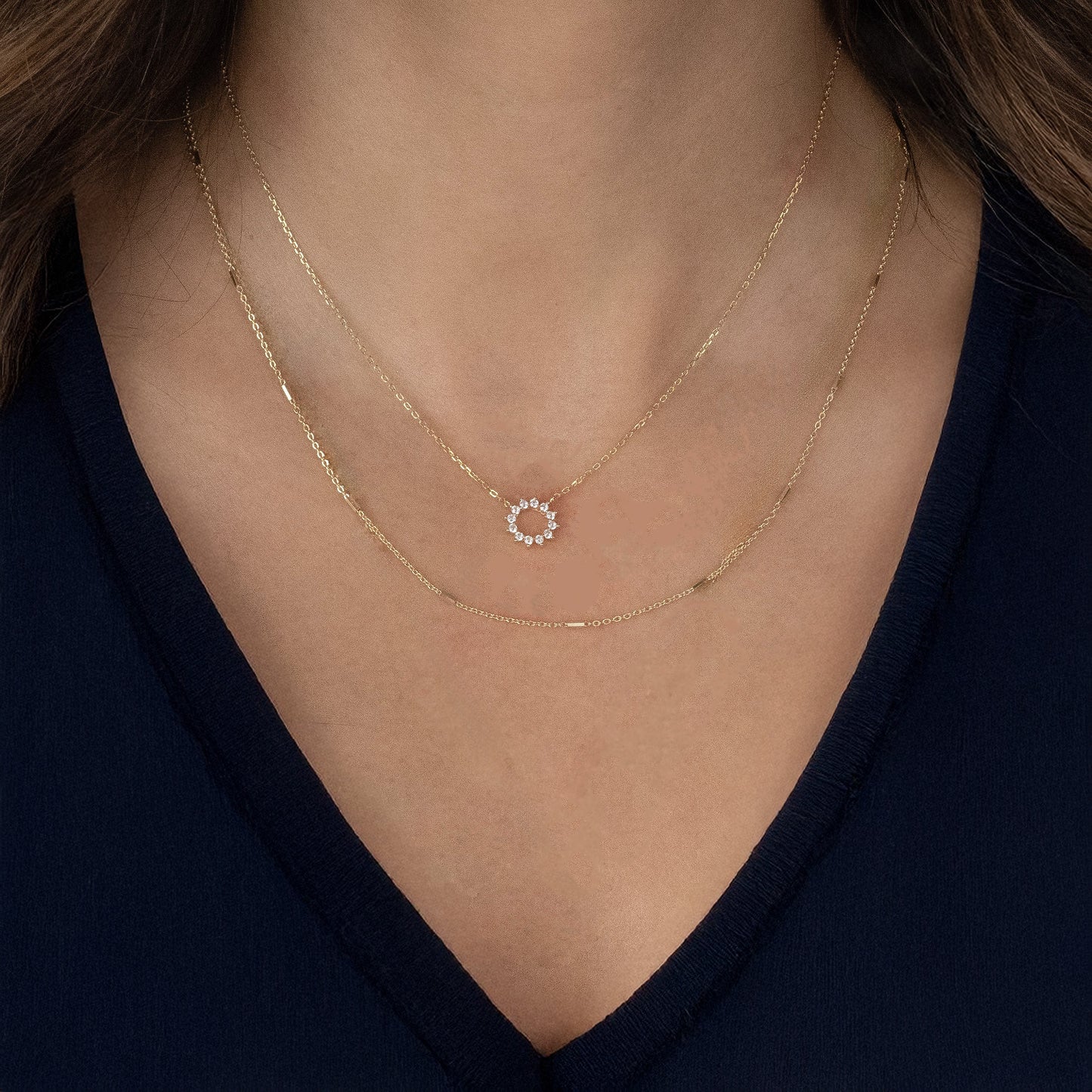 Model wearing a gold-plated sterling silver delicate chain necklace with elongated gold bead-like elements approximately every two inches. The model is also wearing a shorter gold necklace with a sun shaped pendant.