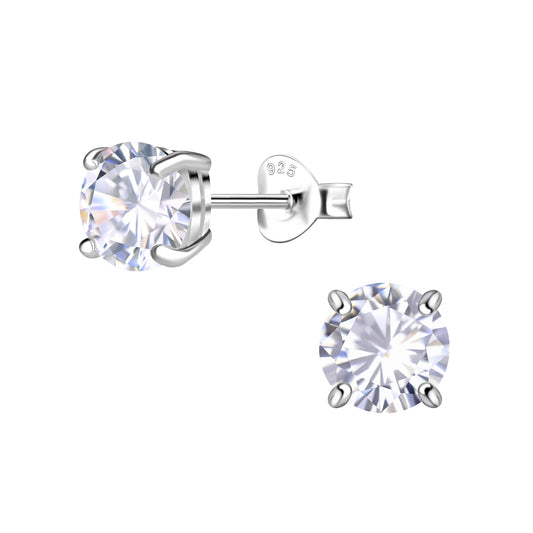 A pair of solitaire stud earrings in sterling silver. The stone is a white cubic zirconia. One earring is offset to show the post and backing. The backing has 925 printed on it to note that the earrings are made from sterling silver.