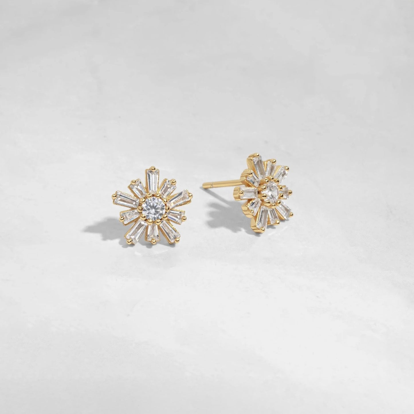 Gold-plated sterling silver flower-shaped studs earrings with 10 petals and a circular stone in the center. Each petal is made of white cubic zirconia in a baguette shape. The center stone is white cubic zirconia. 