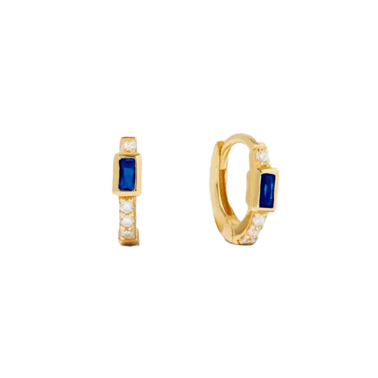 Small gold-plated huggie hoop earrings with a blue baguette-shaped cubic circonia. There is one white cubic zirconia above the blue stone and a line of 3 white cubic zirconias below. 
