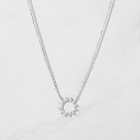 Delicate sterling silver necklace with a circular pendant. The pendant is an open circle with 12 white cubic zirconia stones set around the circumference. 